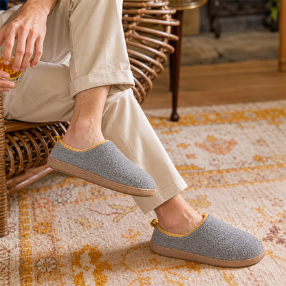 Grey house slippers with yellow lining, worn while sitting in a wicker chair