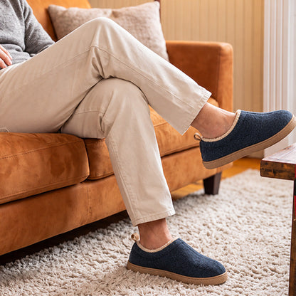 Navy fleece-lined house slippers worn while relaxing on a sofa