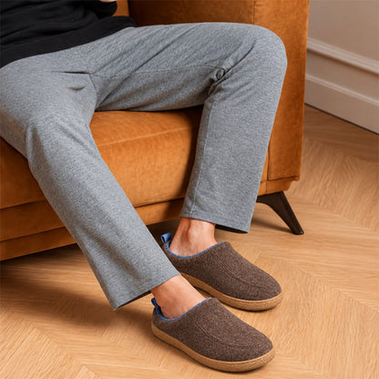 Brown house slippers with blue lining, worn while sitting on a sofa
