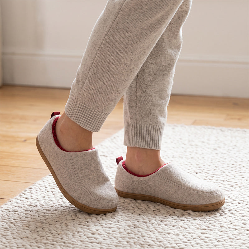 White fleece-lined house slippers worn on a rug, shown from an angled side view