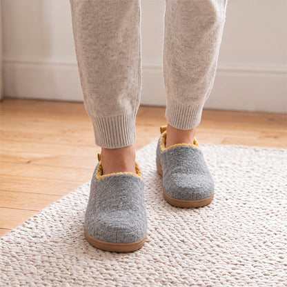 Grey house slippers with yellow lining, shown from the front while worn