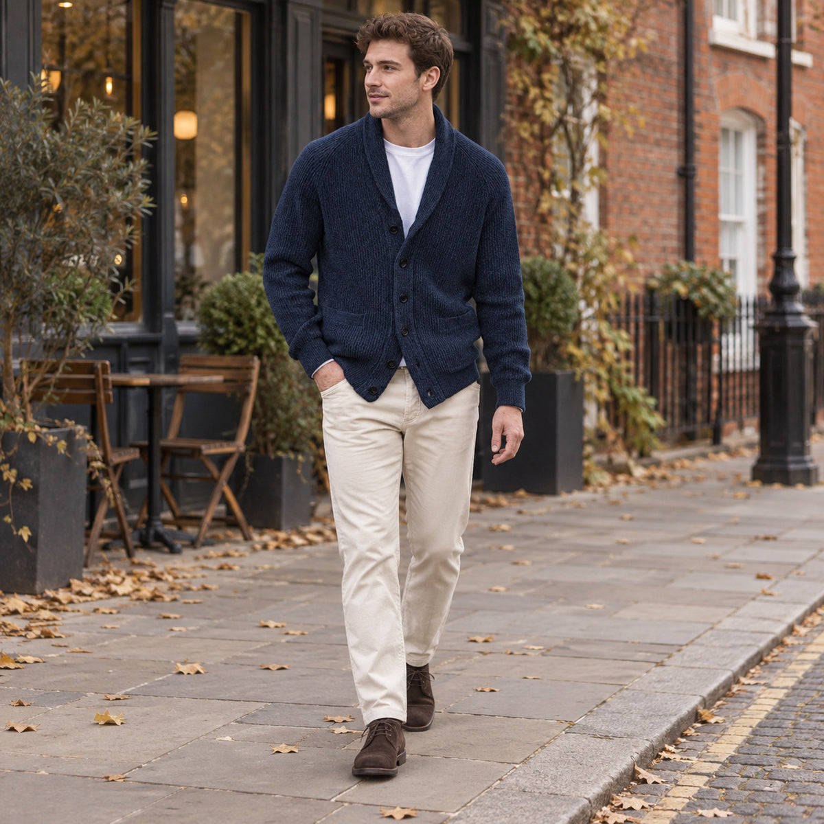 Younger adult man wearing the navy textured shawl-collar cardigan with a white tee and beige trousers on a city street.