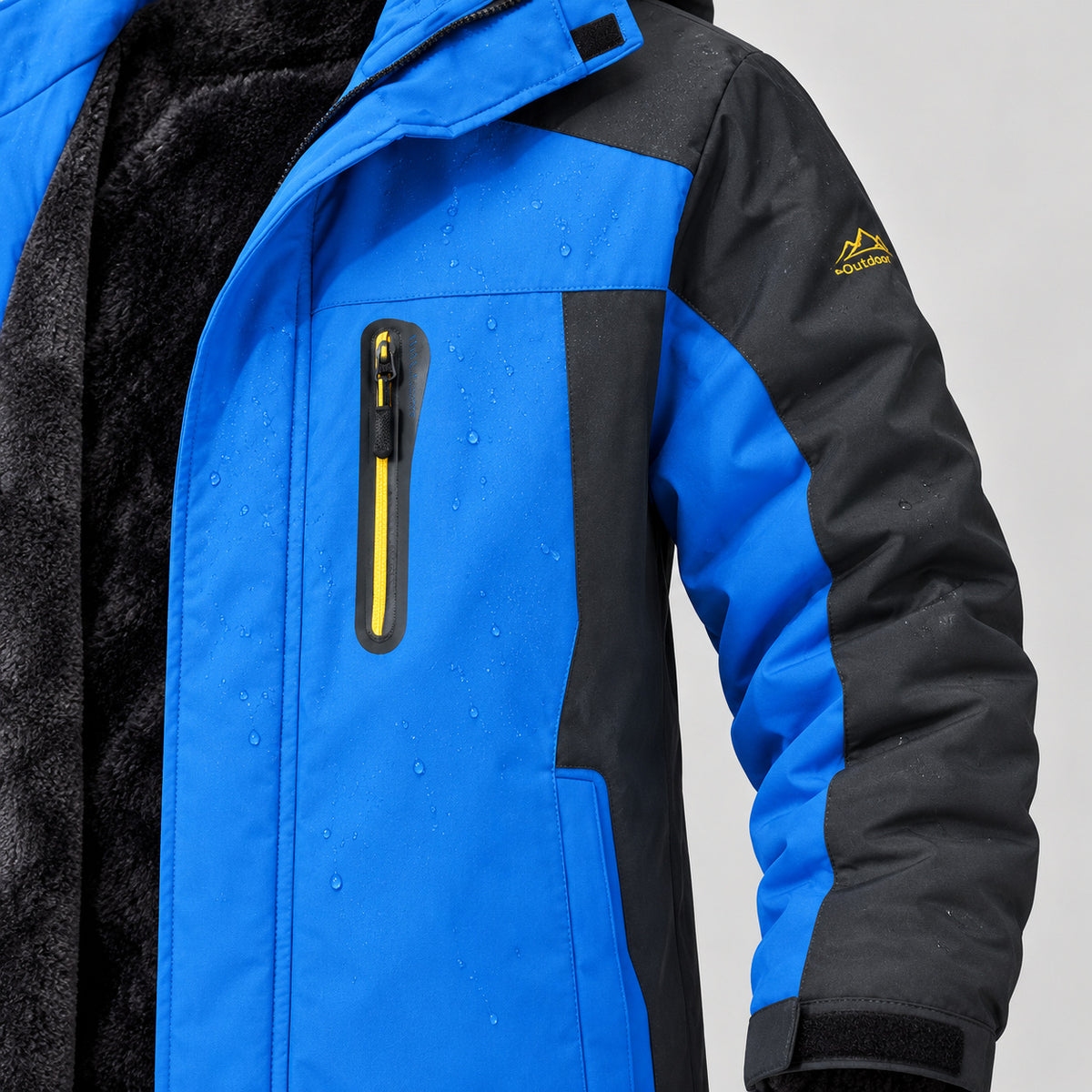 Blue front panel with small surface water droplets, yellow chest-pocket zip, dark sleeve and original gold sleeve mark