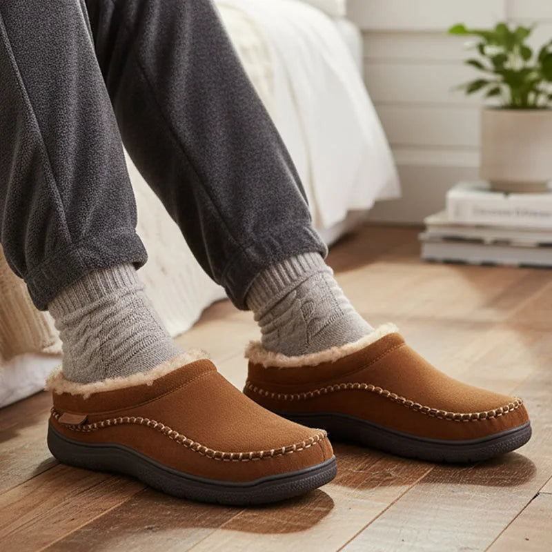 Tan fleece-lined house slippers worn with grey socks on a wooden floor