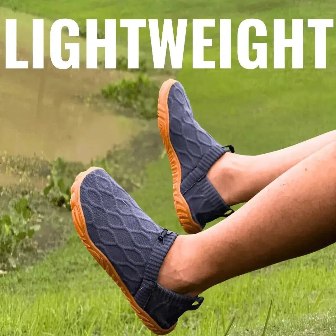 Pair of grey slip-on shoes with orange soles worn outdoors