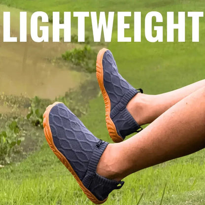 Pair of grey slip-on shoes with orange soles worn outdoors