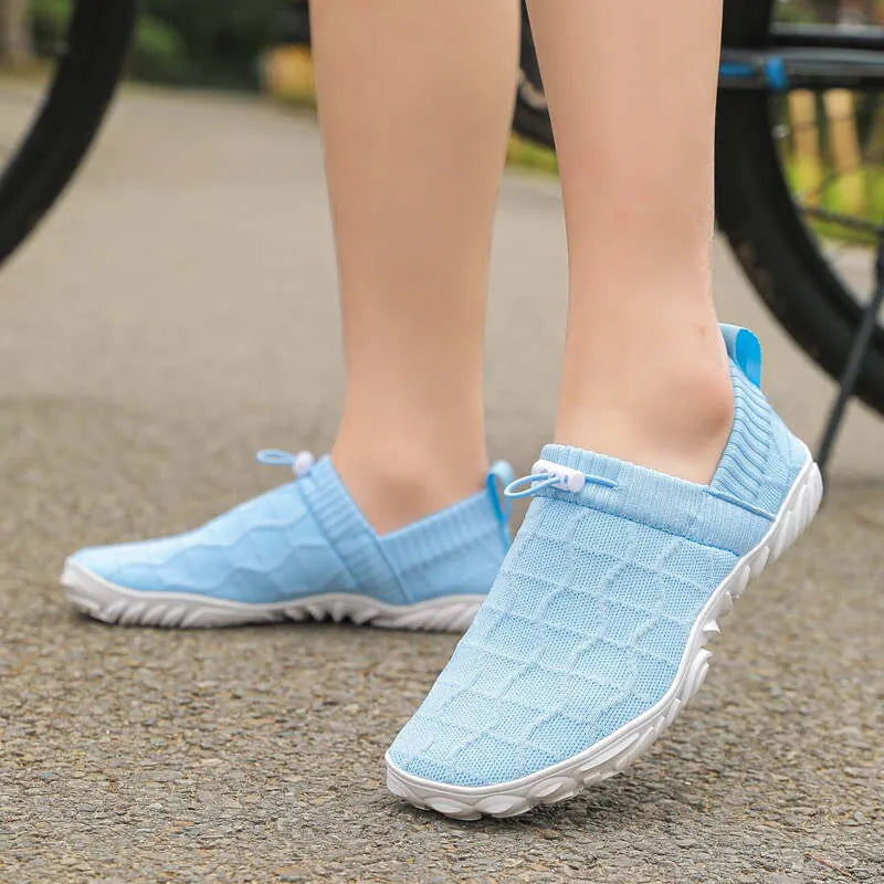 Light blue barefoot-style slip-on shoes worn outdoors with a broad rounded toe shape