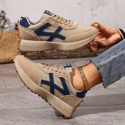Women's beige and navy walking trainers shown on foot and held from the side