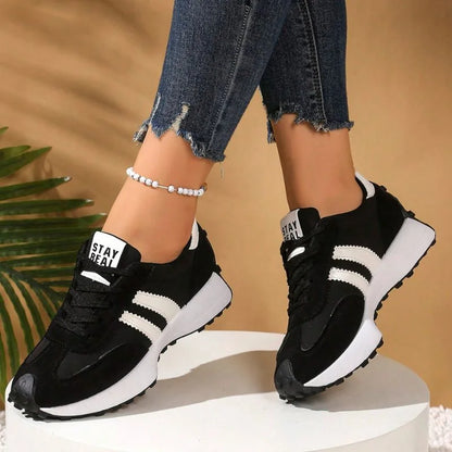 Women's black and white walking trainers worn on a display platform