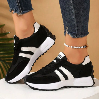Women's black and white walking trainers worn from the side
