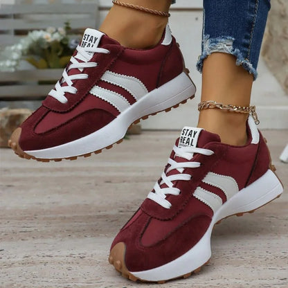 Women's burgundy and white walking trainers worn from the front
