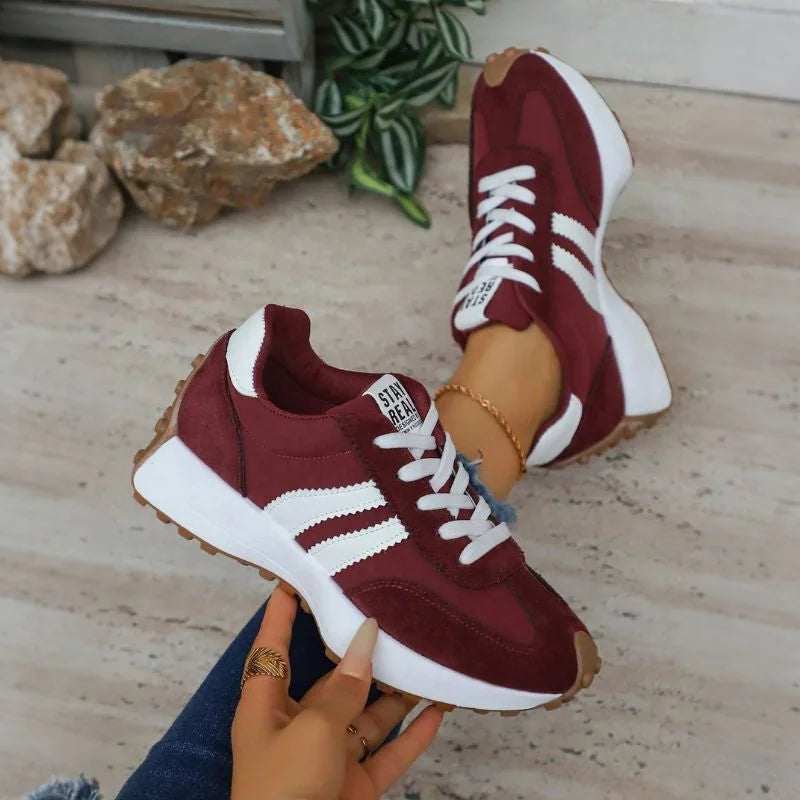 Women's burgundy and white walking trainers shown on foot and held from the side