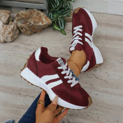 Women's burgundy and white walking trainers shown on foot and held from the side