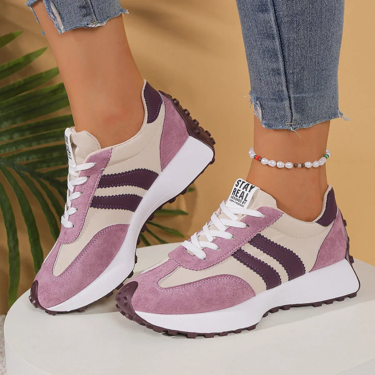 Women's pink, cream and purple walking trainers worn from the side