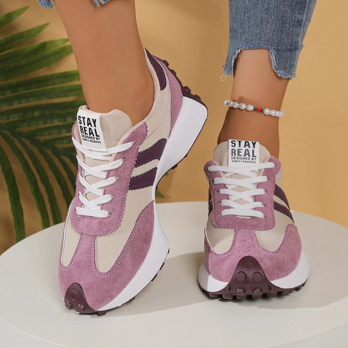 Women's pink, cream and purple walking trainers worn from the front