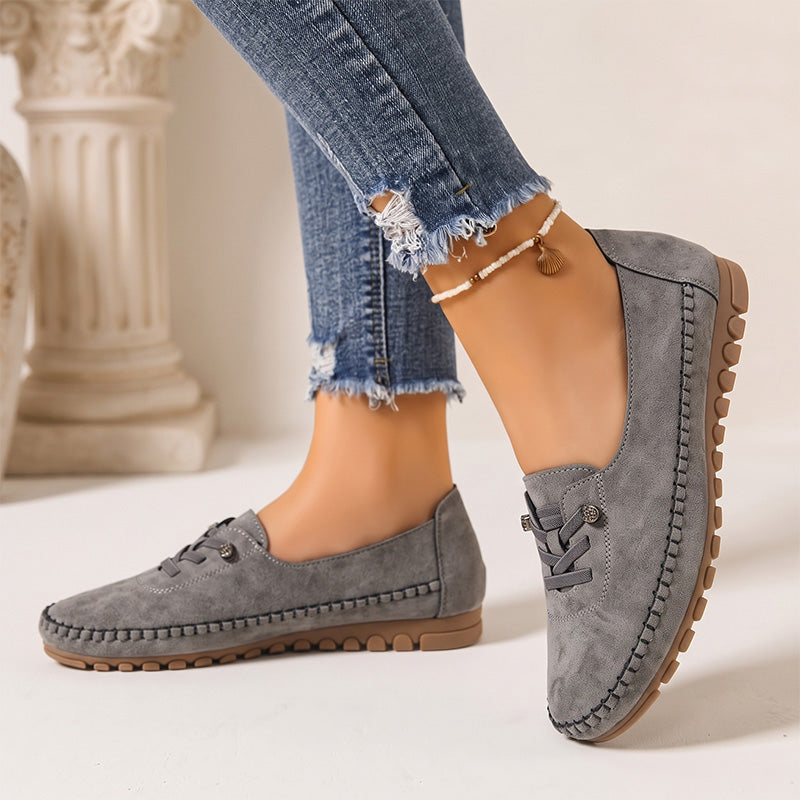 Dark grey women's wide fit suede loafers with brown soles, side view on feet