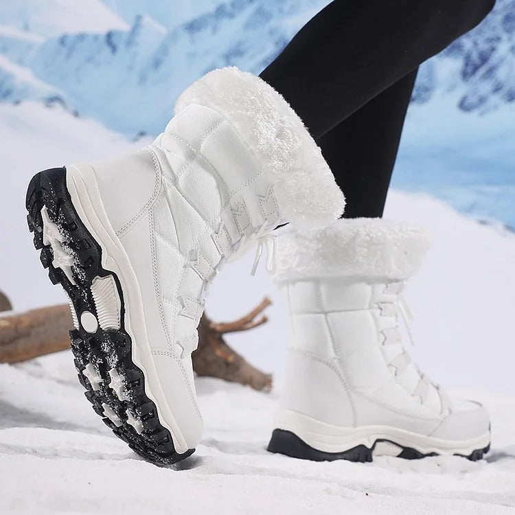 White winter boots showing the textured outsole while worn in snow