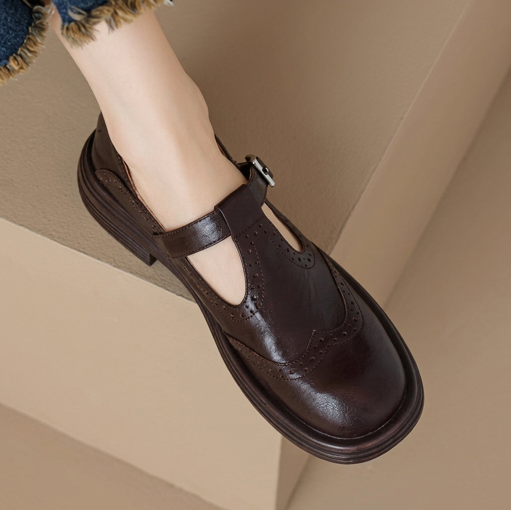 Dark brown women's Mary Jane brogue shoe with adjustable buckle strap, close-up on foot