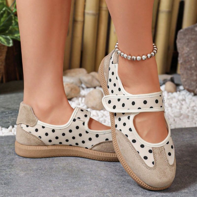 Beige polka-dot women's Mary Jane trainers with gum soles, angled view on feet