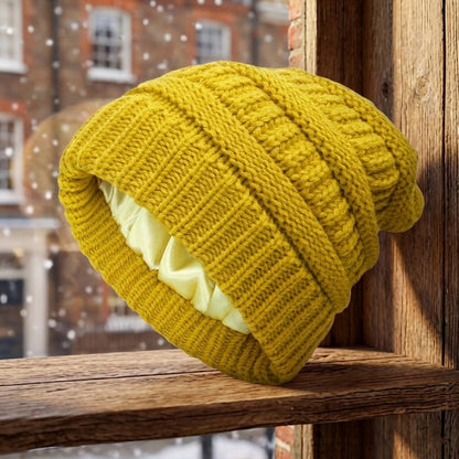 Cable-knit winter beanie – yellow beanie on a wooden stool