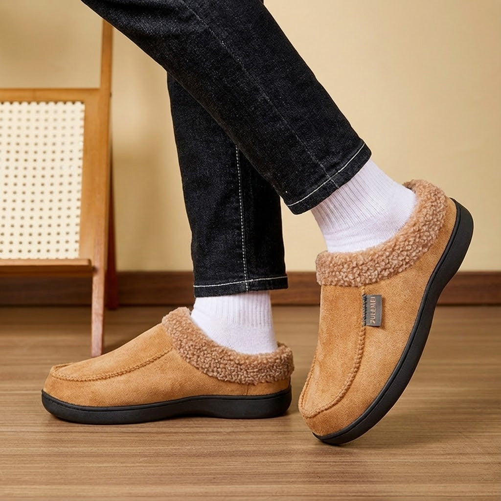 Auldweave Men’s warm wide fit winter slippers. Brown slippers worn with black jeans and white socks on a wooden floor.