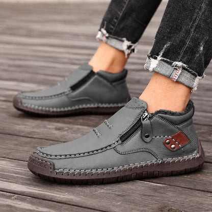 Grey men's leather ankle boots with side zips and contrast stitching, close-up on feet