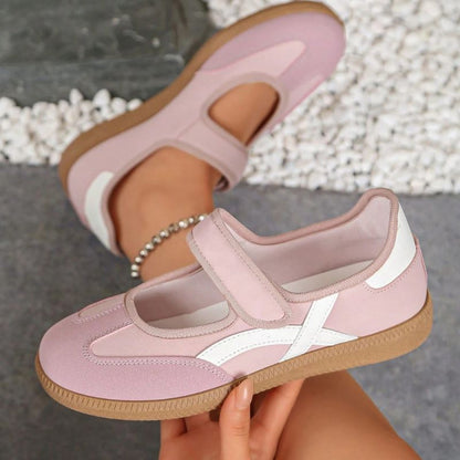 Pink women's Mary Jane trainers with white curved stripes, showing the strap and gum sole