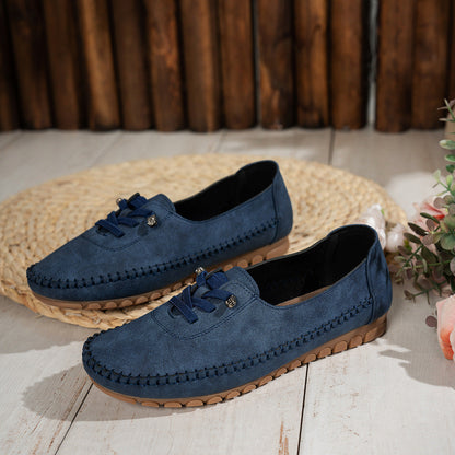 Navy women's suede loafers with stitched edges, pair displayed beside flowers