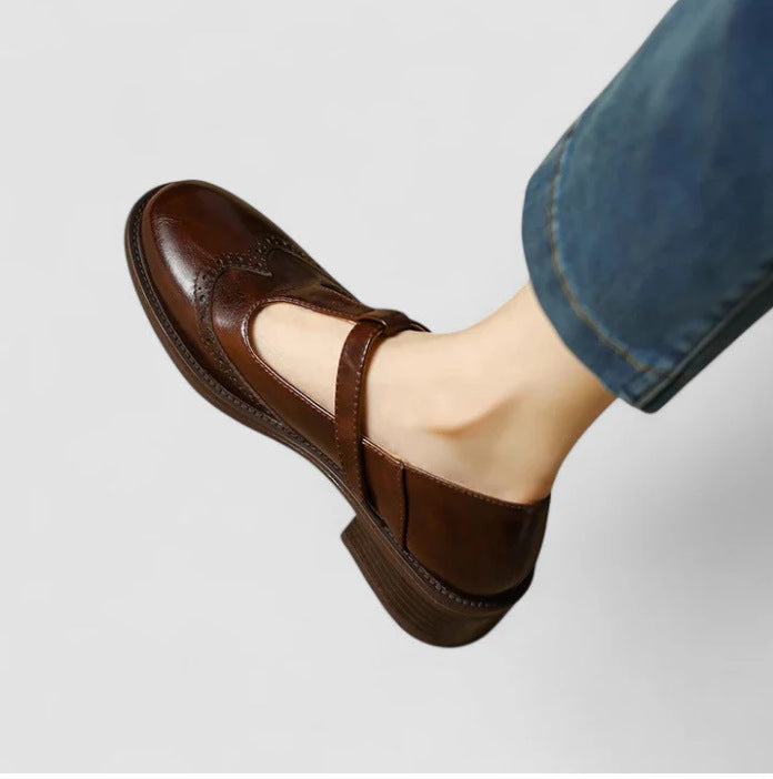 Dark brown women's Mary Jane brogue flat with buckle strap, worn with jeans