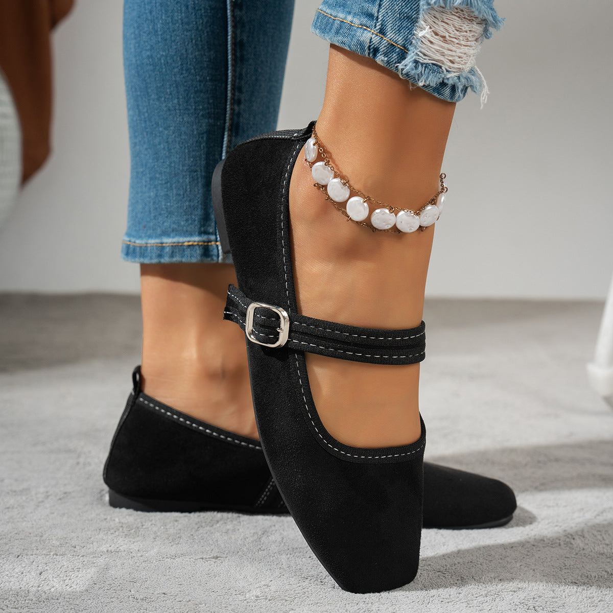 Black women's Mary Jane flats with silver-tone buckles, worn with jeans