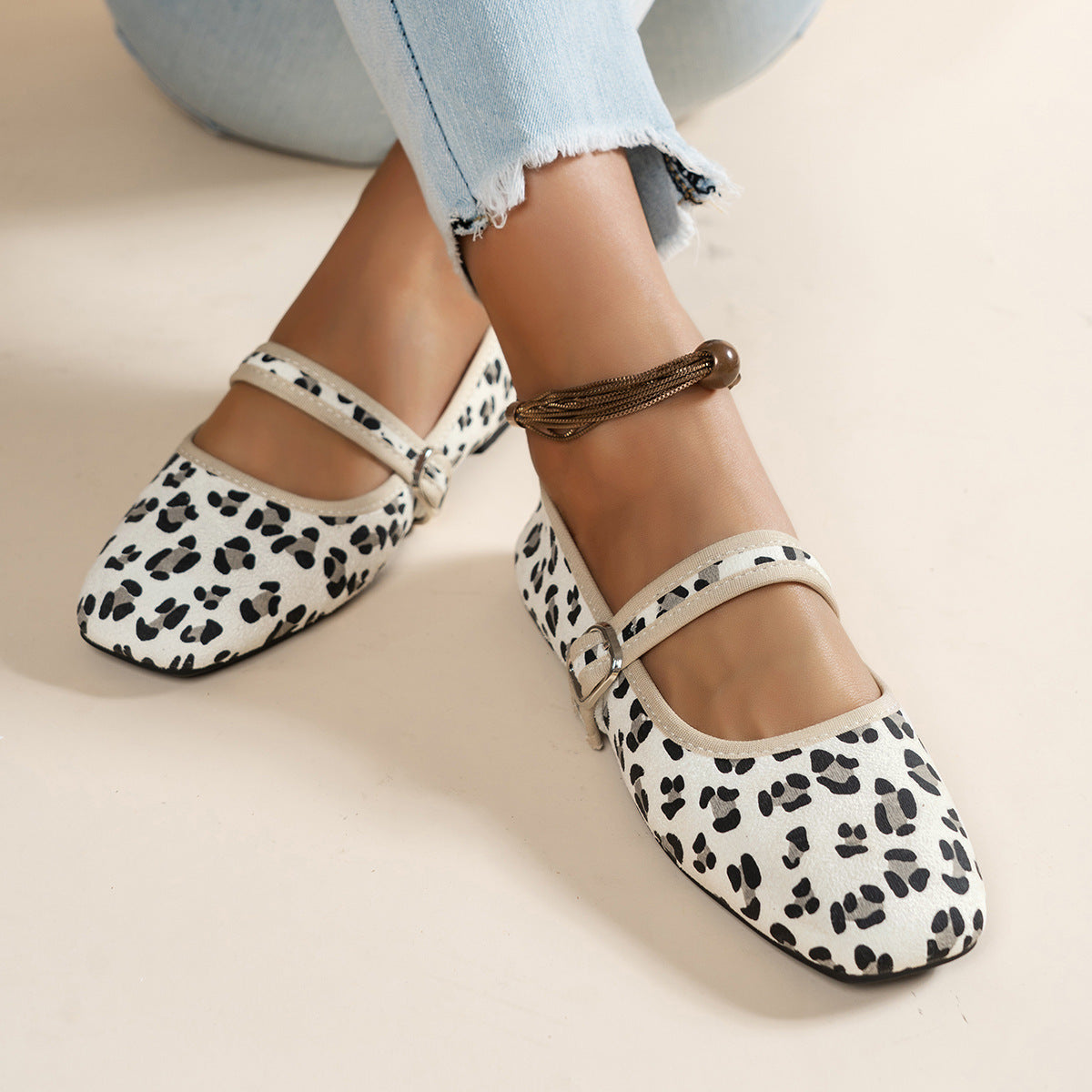 Cream women's Mary Jane flats with black animal-print spots, top view on feet