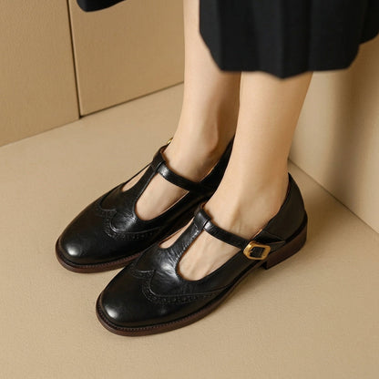 Black women's Mary Jane brogue flats with gold-tone buckles, front view on feet