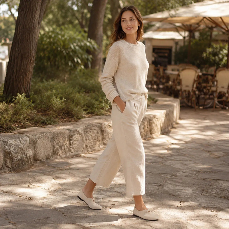 Cream women's suede loafers styled with an ivory outfit on a garden path