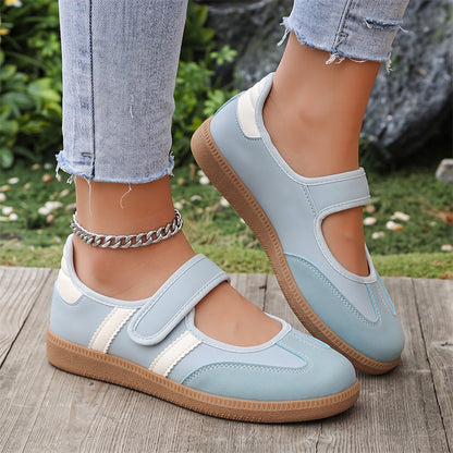 Light blue and white women's Mary Jane trainers with adjustable straps, close-up on feet
