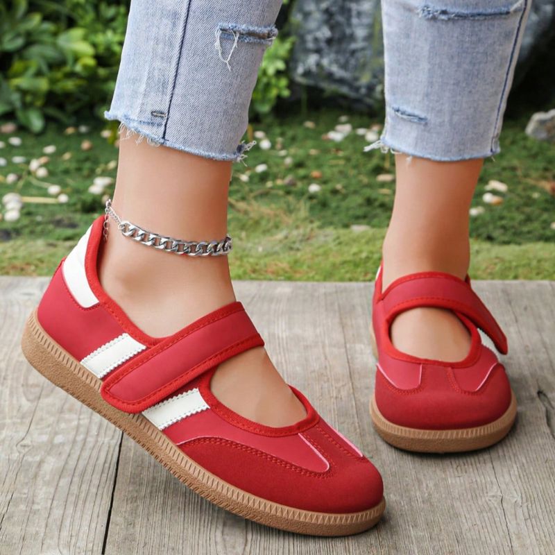 Red and white women's Mary Jane trainers with adjustable straps, front view on feet