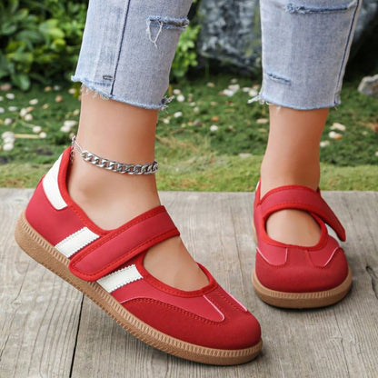 Red and white women's Mary Jane trainers with adjustable straps, front view on feet