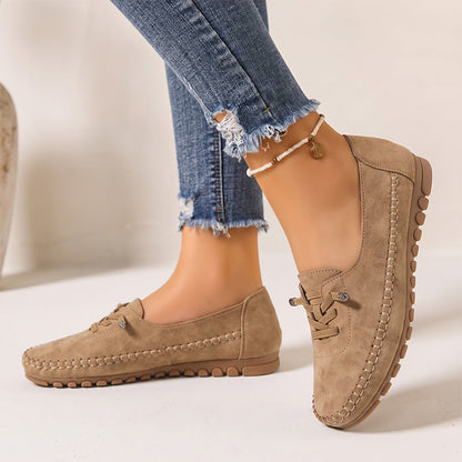 Tan women's wide fit suede loafers with brown soles, side view on feet