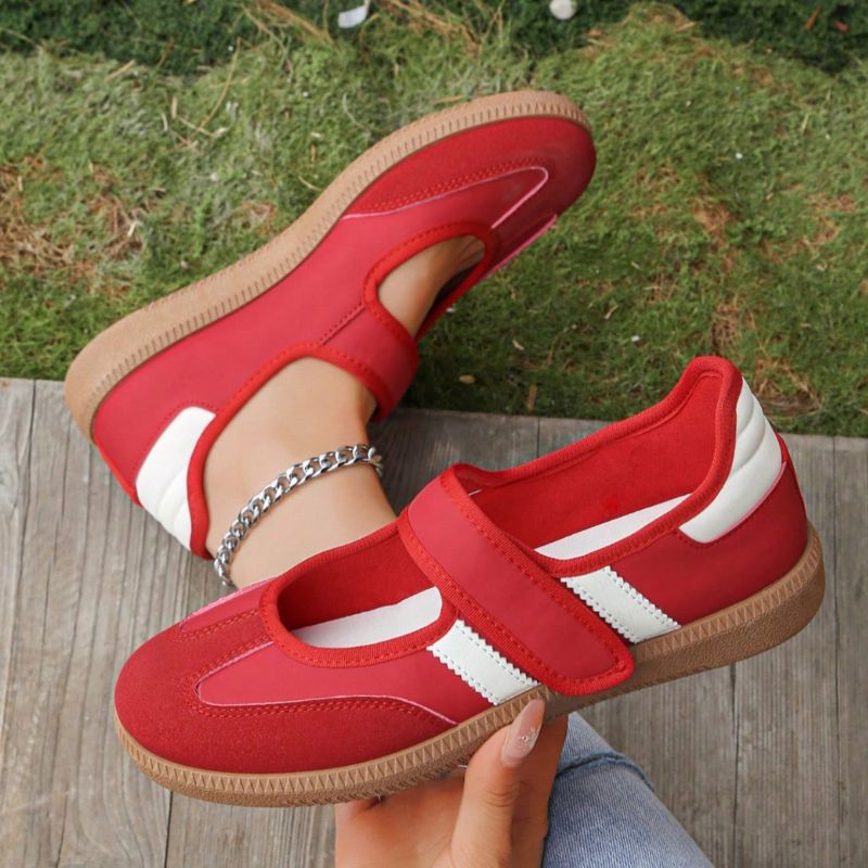 Red women's Mary Jane trainers with white stripes, showing the strap and gum sole
