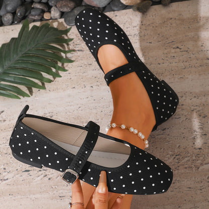 Black polka-dot women's Mary Jane flats showing the buckle strap and pale lining