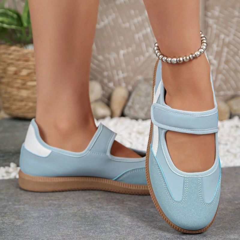 Blue women's Mary Jane trainers with adjustable straps and gum soles, front view on feet