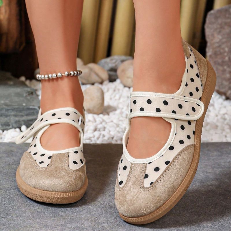 Beige women's Mary Jane trainers with black polka dots and broad straps, front view on feet