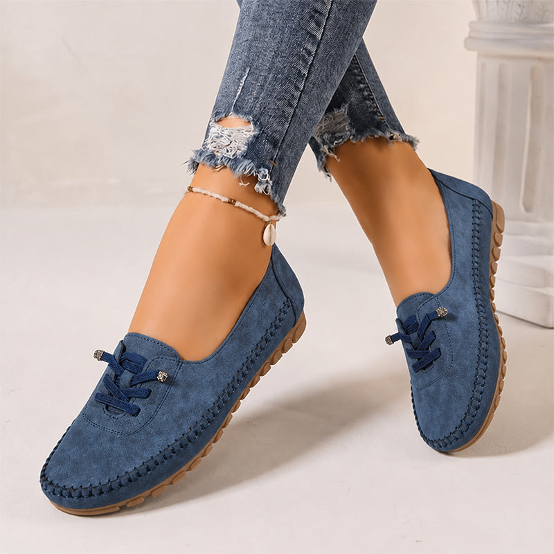 Navy women's suede slip-on loafers with rounded toes, angled view on feet