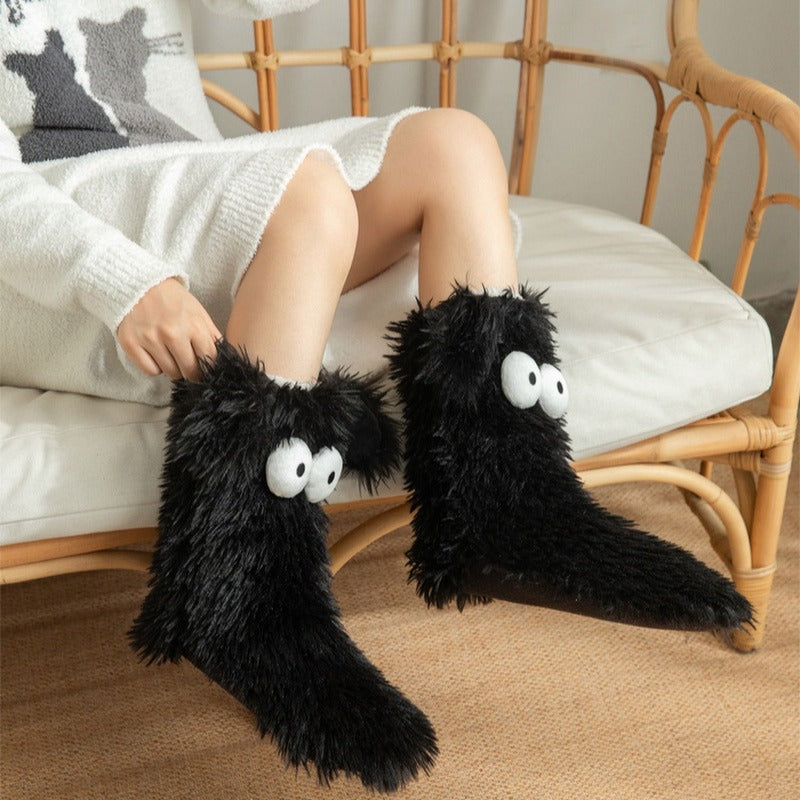 Fluffy dog slipper socks – black pair worn on a chair