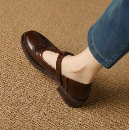 Dark brown women's Mary Jane brogue flat showing toe perforations and T-bar strap on foot