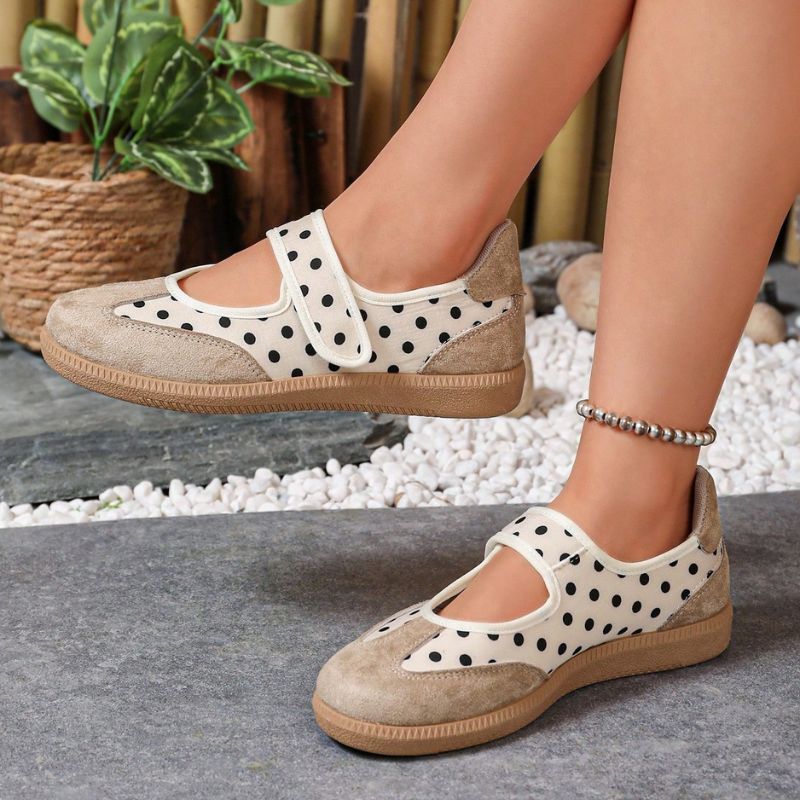 Beige polka-dot women's Mary Jane trainers with adjustable straps, side view on feet