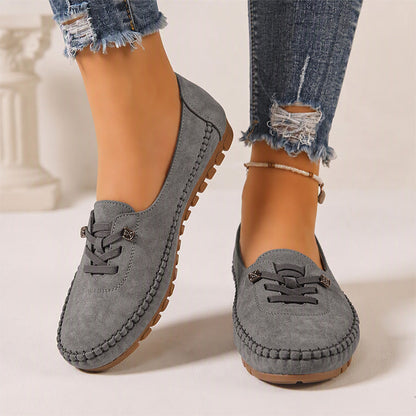 Dark grey women's suede slip-on loafers with stitched edges, front view on feet