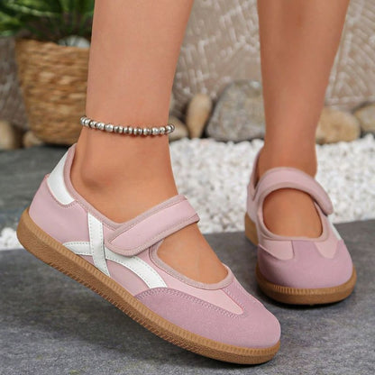 Pink women's Mary Jane trainers with white curved stripes, side view on feet