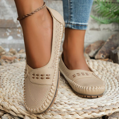 Beige women's perforated leather loafers with decorative cut-outs, front view on feet
