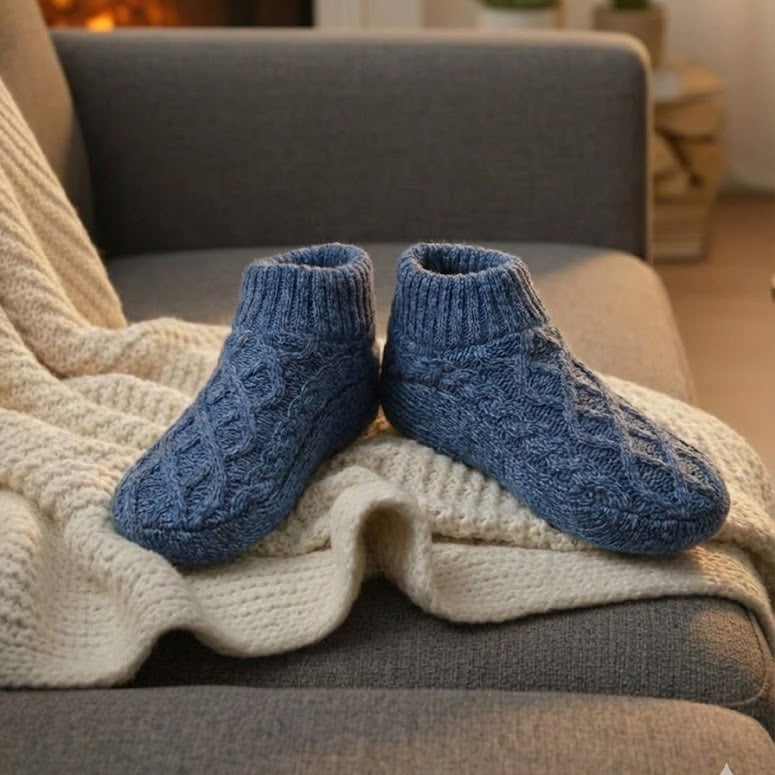 Auldweave women's knitted non-slip indoor slippers – blue pair beside a fireplace