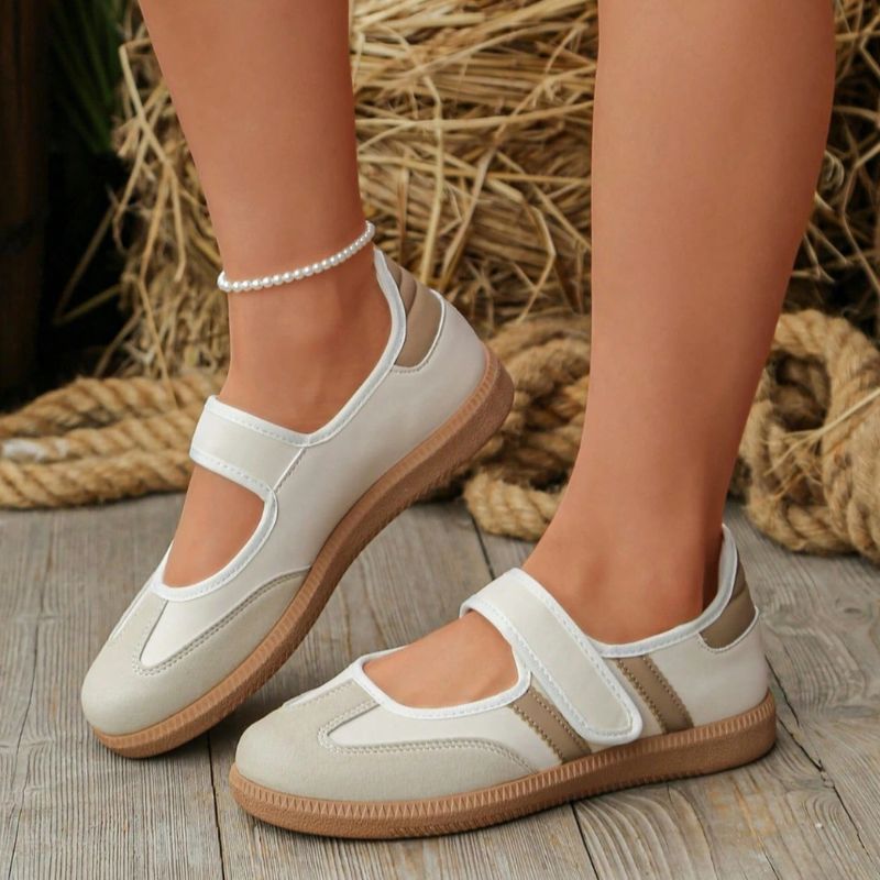 Beige and white women's Mary Jane trainers with adjustable straps, side view on feet